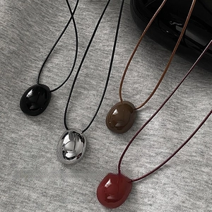 Minimalist wax cord necklace with pebble shaped oval pendants in four colors