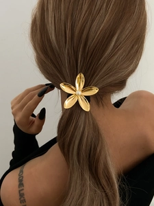 Detail of a golden flower hair accessory with a white pearl on a elegant ponytail