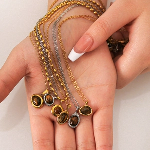 Vintage stainless steel necklaces with oval tiger eye pendants held by hand