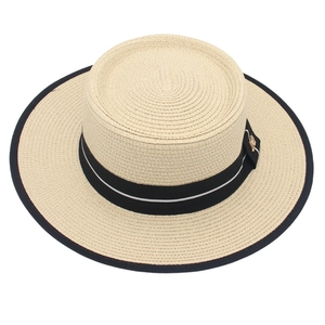 Dettaglio cappello di paglia beige con nastro in gros-grain nero e fibbia dorata