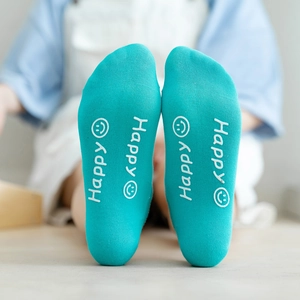 Macro shot of blue cotton sock sole with white Happy text and smiley face pattern