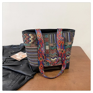 Close-up of ethnic tote bag with geometric patterns and leather base on a wooden desk