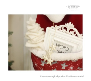 Detail of red Christmas stocking with white angel print and three golden sequin stars