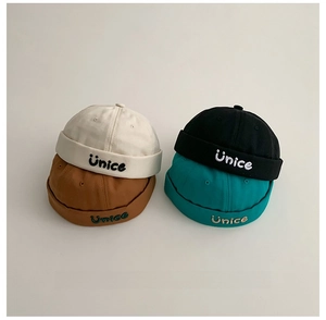 Dettaglio di quattro cappelli miki in cotone per bambini con ricamo Unice e sorriso