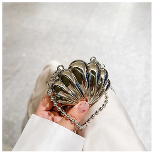 Close-up of a mini silver metallic shell-shaped clutch bag with delicate bead chain strap