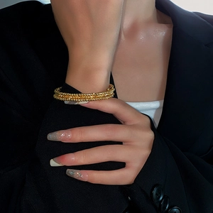 Close-up of elegant gold beaded multilayer cuff bracelet on a female model
