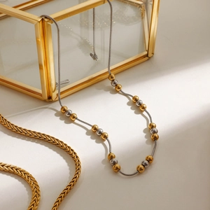 Close-up of mixed gold and silver beads on a stainless steel snake chain necklace
