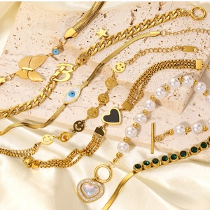 Detail of gold-plated chain bracelets with pearls and charms on champagne silk