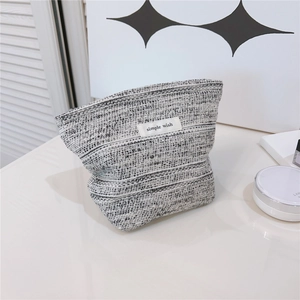 Detail of black and white woven tweed makeup bag with simple wish textile label