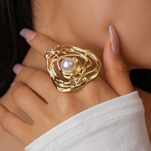 Detailed view of oversized gold irregular hollow ring with centered white pearl on hand