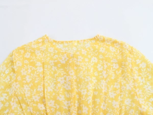 Close-up of yellow floral tea dress featuring a V-neckline and breathable fabric