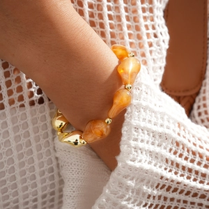 Gros plan du bracelet bohème avec perles en résine ambre et perles dorées