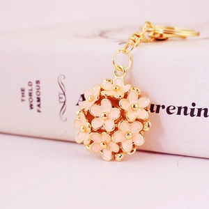 Golden keychain with a 3D hollow pink enamel flower ball charm on a soft background