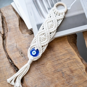 Detail of macrame wall hanging with wooden ring and blue Turkish evil eye glass bead