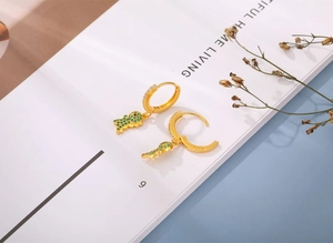 Detailed close-up of S925 silver dinosaur earring with green zircon and gold plating