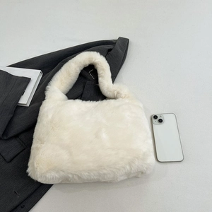 Size comparison of the white plush tote bag with a smartphone and a suit jacket
