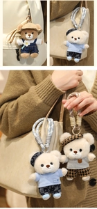 Close-up of cute plush teddy bear bag charms with colorful braided ropes and metal clasps