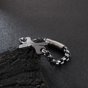 Macro detail of industrial steel bracelet with wrench and screwdriver charms on aged wood