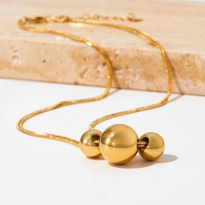 Minimalist gold necklace with three metallic spheres on a sleek snake chain for women