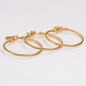 Three gold stainless steel cable bracelets with horseshoe buckle shackles on white background