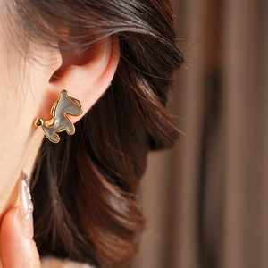 Macro detail of 18K gold plated poodle earring with gray enamel finish on earlobe
