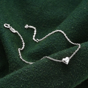 Close-up of polished silver heart charm on a minimalist S925 sterling silver chain bracelet