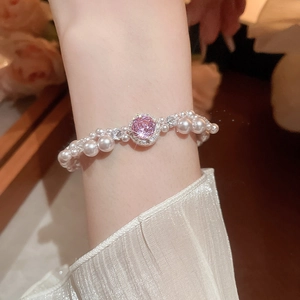 Detail of pink zircon and pearl triple layer bracelet on woman's wrist in elegant style