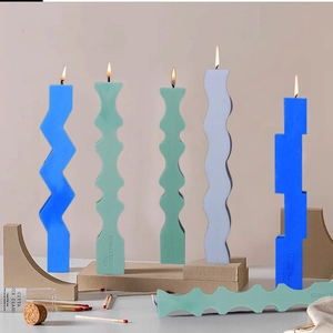 Artistic geometric scented candles in blue and green hues on a decorative pedestal