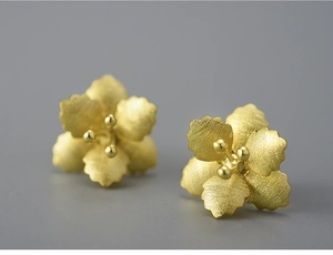 Macro view of gold flower stud earrings featuring matte brushed finish and 925 silver core