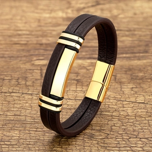 Close-up of brown braided leather bracelet with golden metal accents on wood surface