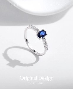 Macro detail of asymmetric silver ring featuring oval blue stone and side diamond accents