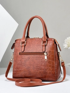 Detailed view of brown crocodile-embossed leather tote with gold hardware and dual handles