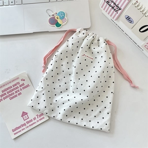 Detailed view of white polka dot drawstring pouch with a red SOZAKKA brand logo label