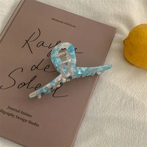Detailed close-up of a blue and white marble resin hair claw clip on a French book