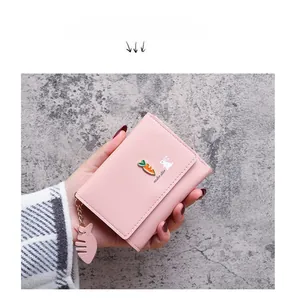 Close-up of pink women's wallet featuring cute rabbit, carrot motifs and fish zipper charm