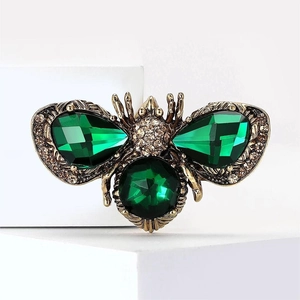 Macro shot of bee brooch with green faceted gemstones and sparkling white rhinestones