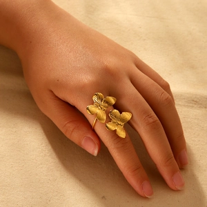 Bague dorée élégante avec deux fleurs et texture brossée sur la main de femme
