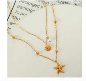 Macro detail of gold double-layer necklace with starfish, shell, and pearl pendants