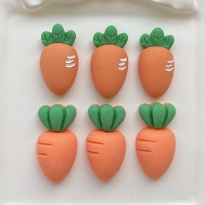 Close-up of six orange resin carrots with green leaves on a white tray for DIY crafts