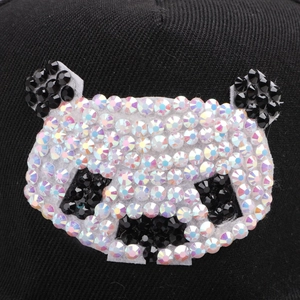 Macro detail of cartoon panda pattern with shimmering rhinestones on black cotton flat brim hat
