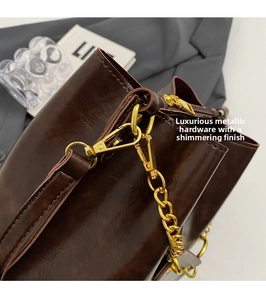 Close-up of dark brown glossy leather texture and gold hardware detail of the bucket bag