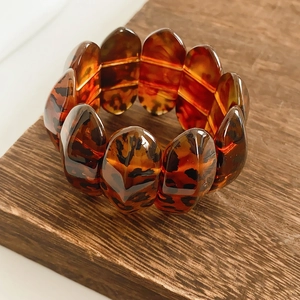 Macro detail of amber leopard print resin bracelet on a vintage wooden base