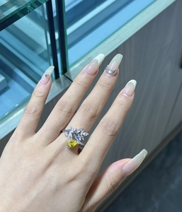 Detailed view of leaf-shaped silver ring featuring a pear-cut yellow gemstone on hand