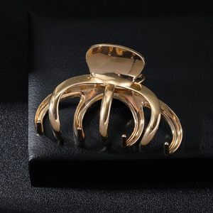 Detailed view of large golden octopus hair claw clip on black premium display stand