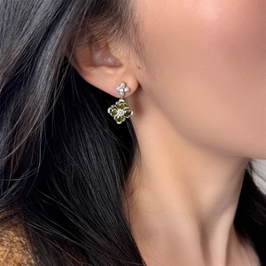 Elegant silver flower earrings with pearls and green gemstone pendants on a model