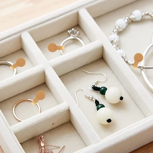 Close-up of kraft paper price tags on jewelry inside a beige velvet display tray