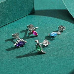 S925 sterling silver dinosaur earrings set with colorful zircon stones on textured background