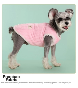 Close-up of pink fleece dog vest with plush white pom-pom trim and soft texture details