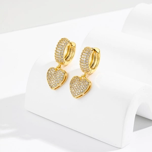 Elegant gold plated heart earrings with sparkling pavé crystals on white geometric props