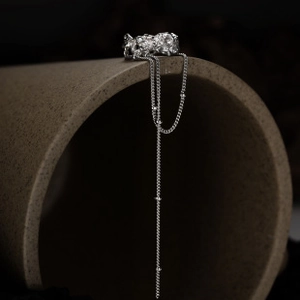 Detail of silver chain ring featuring long tassel and irregular lava texture on ring band